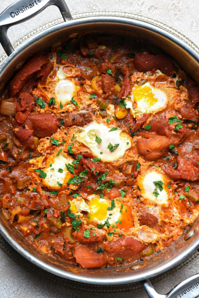 Overhead shot of a large pan willed with tomatoes, eggs and parsley