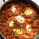 overhead shot of a large pot filled with shakshuka and sprinkled with parsley