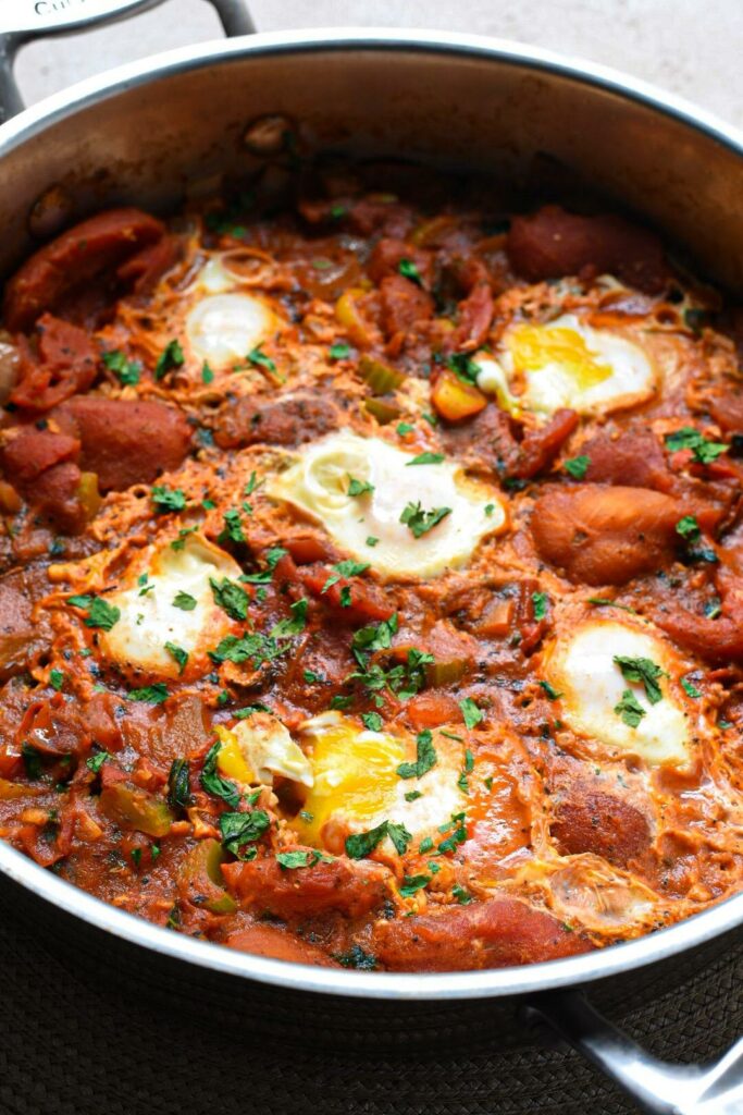 Close up photo of shakshuka with six eggs and parsley