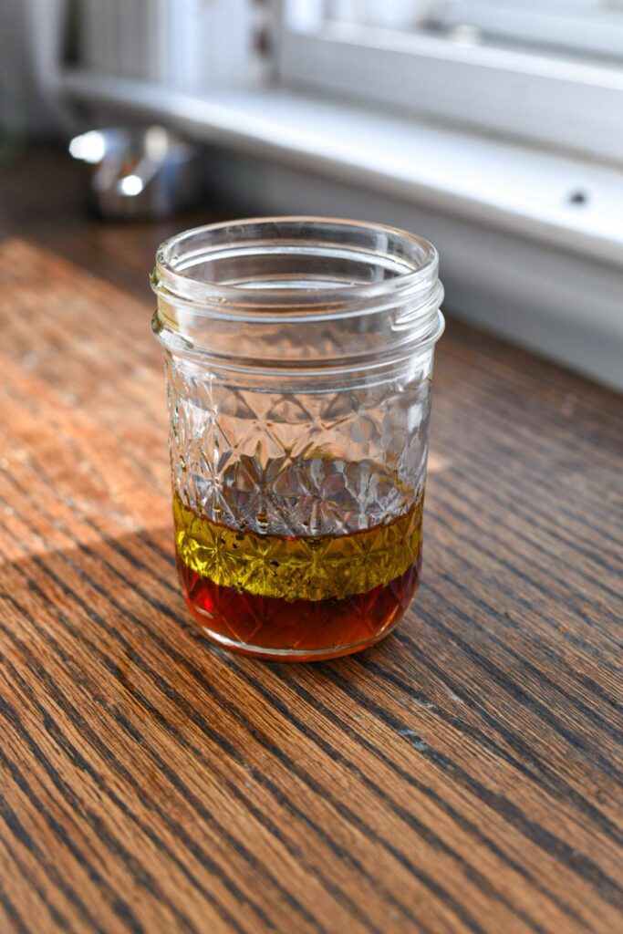 a small glass mason jar filled with oil and vinegar, which has separated