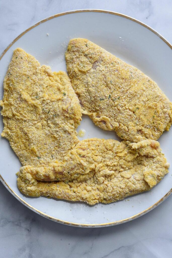 a white plate filled with three thin cut chicken breasts that have been coated in breadcrumbs