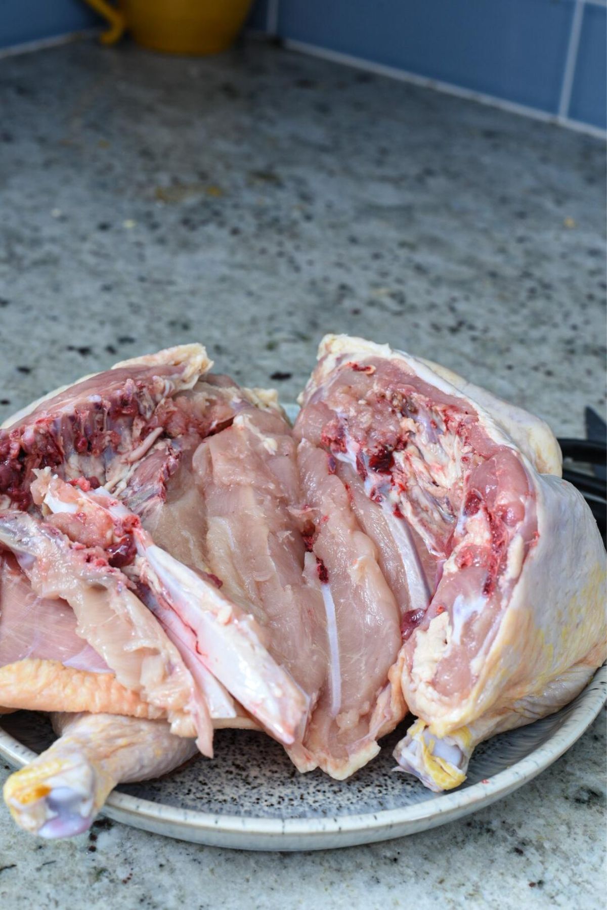 A spatchcocked chicken opened up on a granite counter top