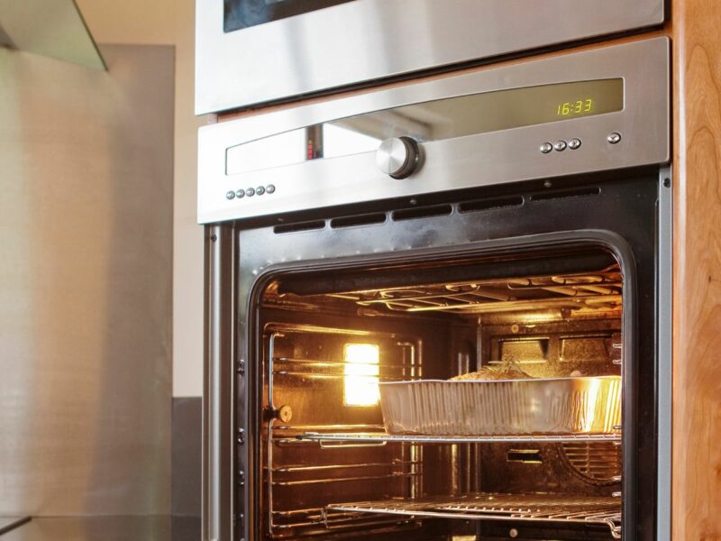 A photo of an open oven with a built in microwave above it