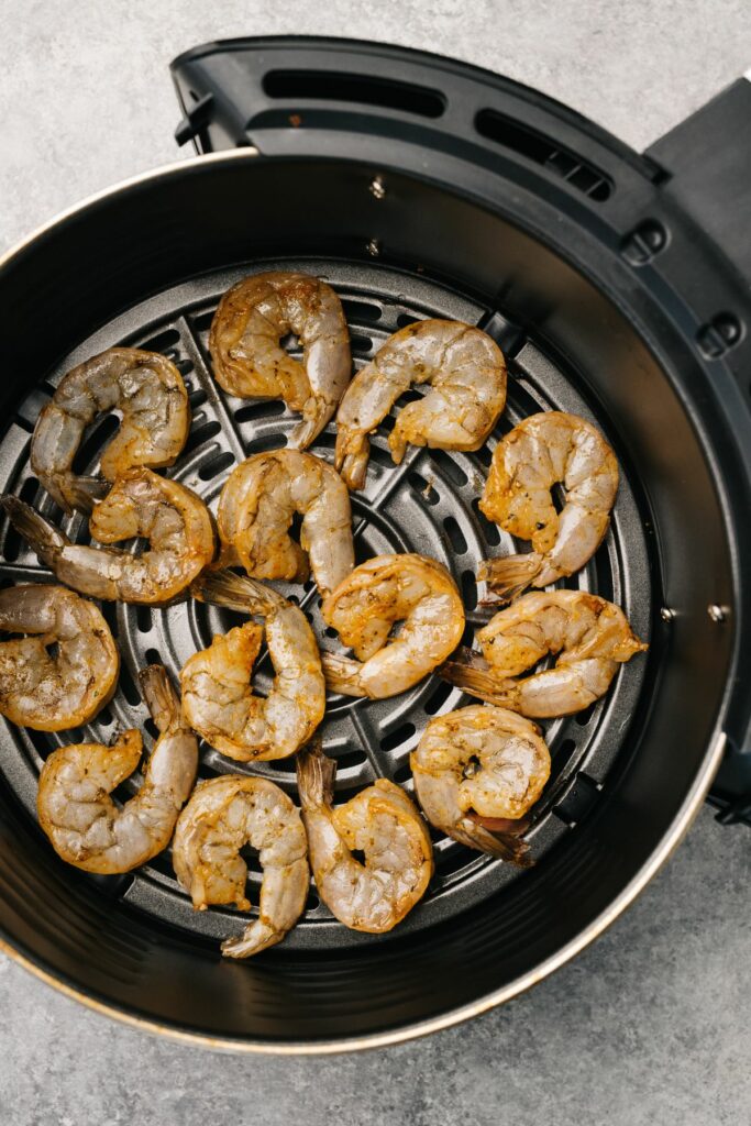 An overhead shot of a bunch of shrimp cooking inside of an air fryer