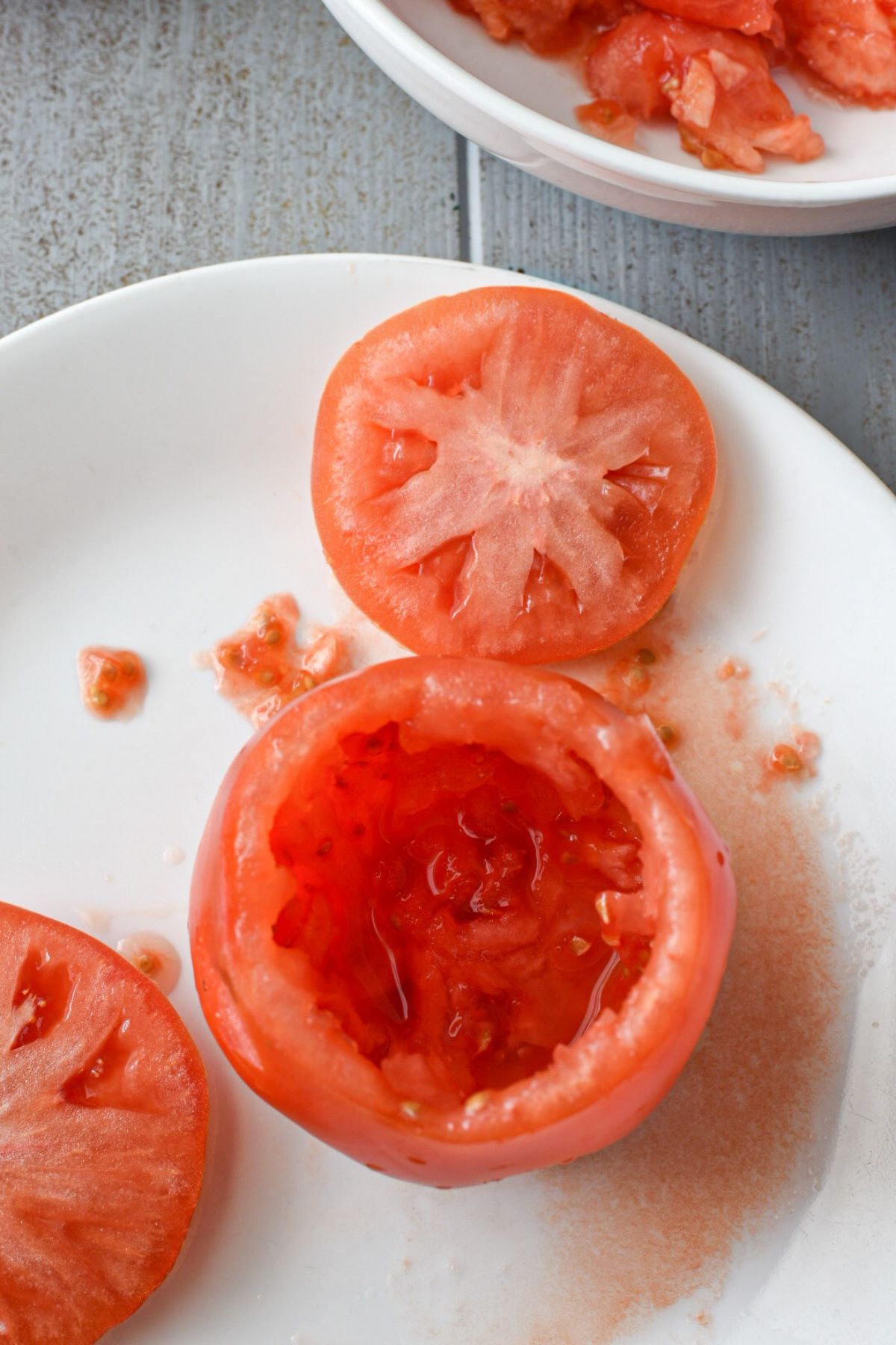 A large beefsteak tomato with the top cut off and the inside of the tomato hollowed out