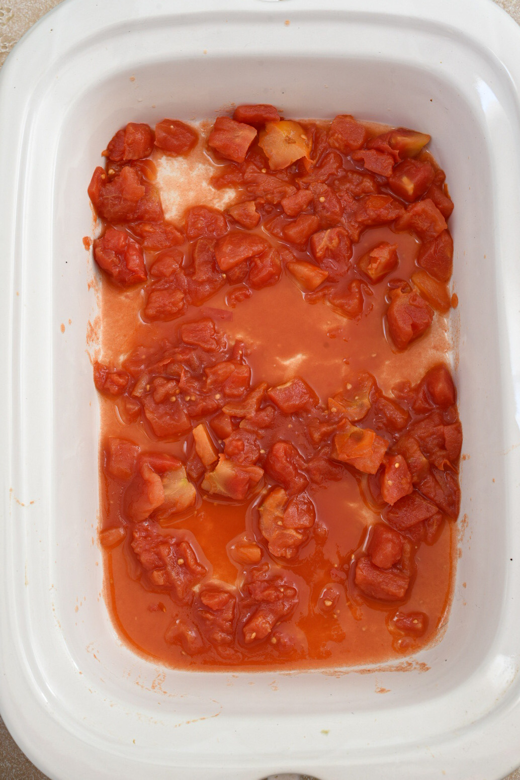 A slow cooker filled with canned diced tomatoes