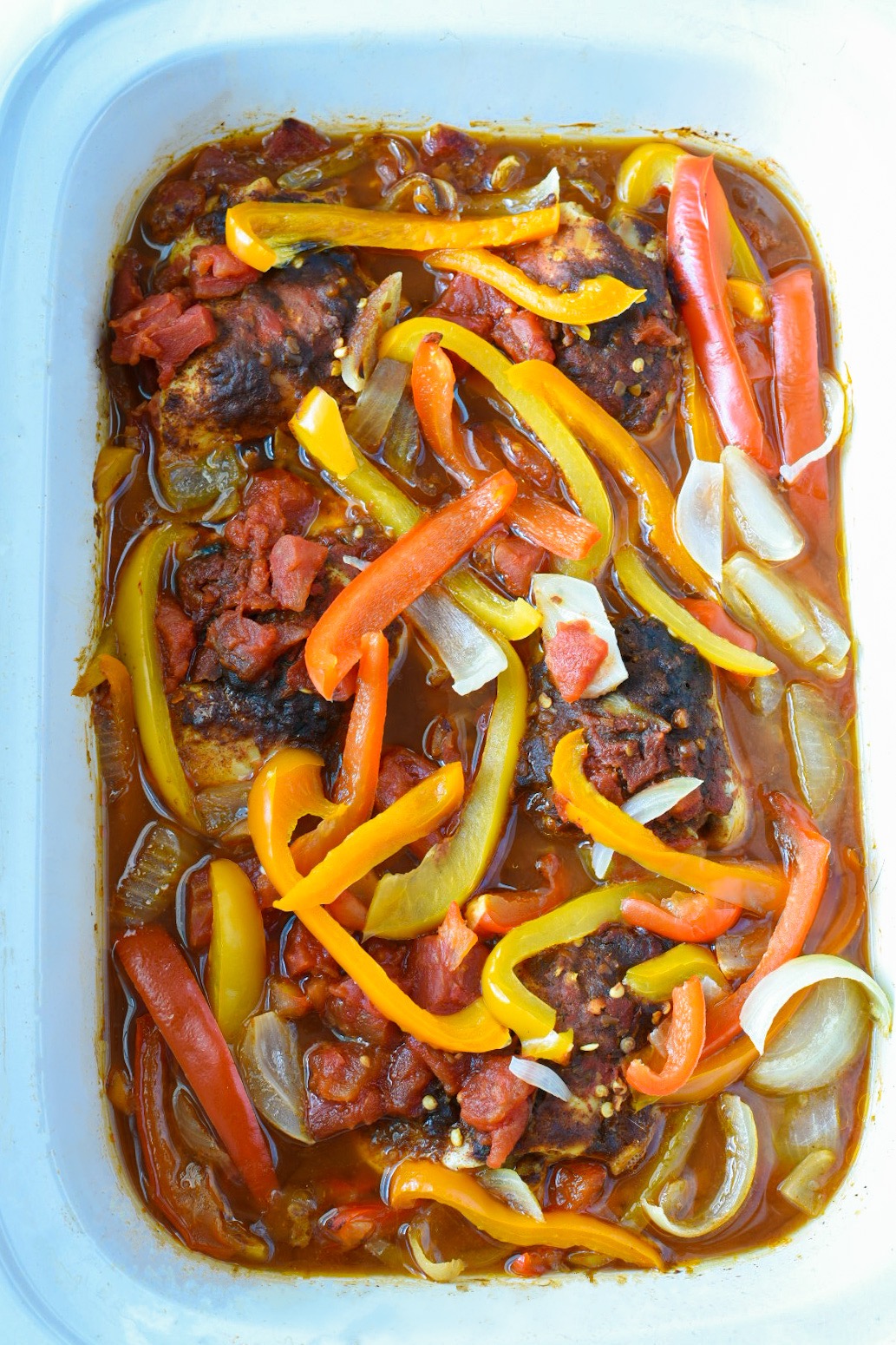 Cooked chicken fajitas in crockpot topped with colorful bell peppers