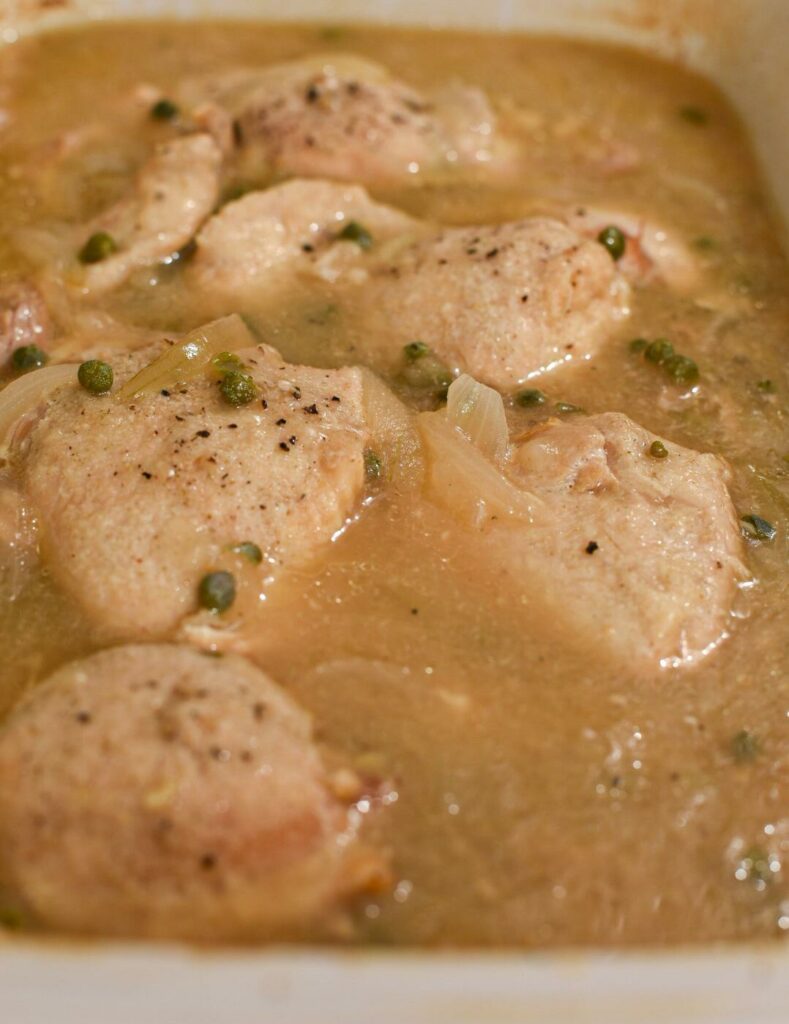 Chicken fully cooked in a slow cooker surrounded by lemon gravy sauce