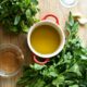 A wooden cutting board with a small bowl of olive oil, salt, red pepper flakes, garlic, vinegar, parsley, and mint