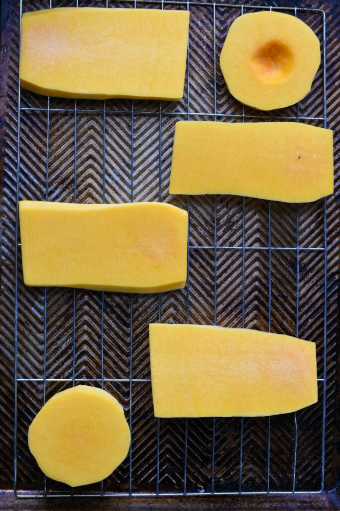 Raw butternut squash steaks on a wire rimmed baking sheet