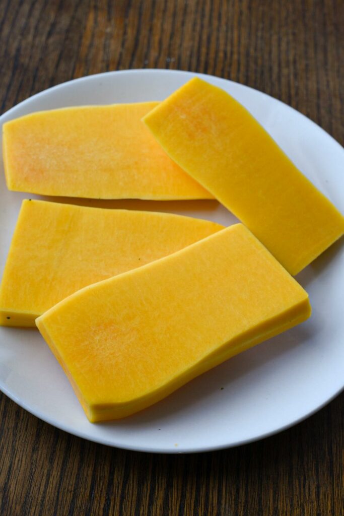 Four bright yellow butternut squash steaks on a white plate