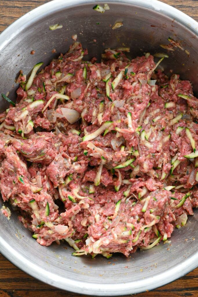 A metal mixing bowl filled with mixed zucchini meatloaf mixture
