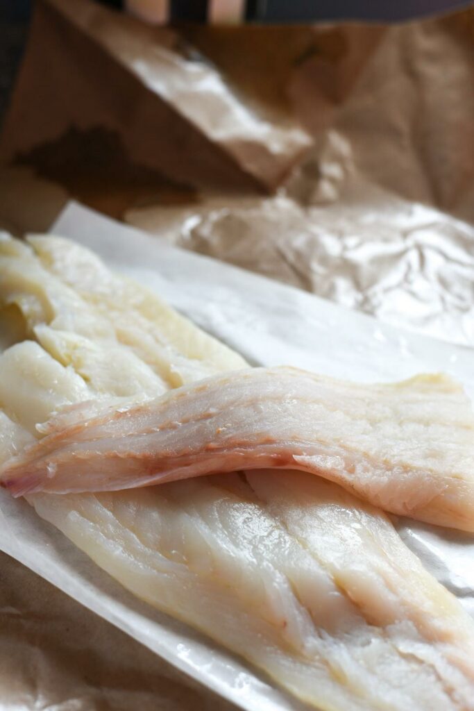 Raw scrod fish opened up on brown fish wrapping paper