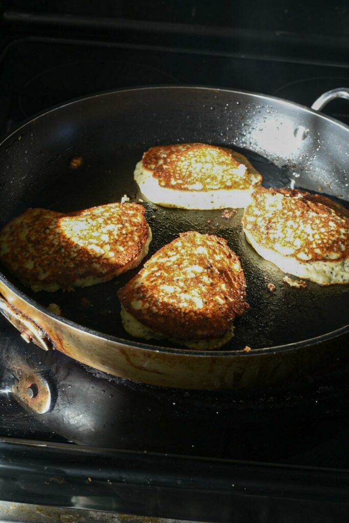 A non-stick skillet with four almond flour banana pancakes cooking