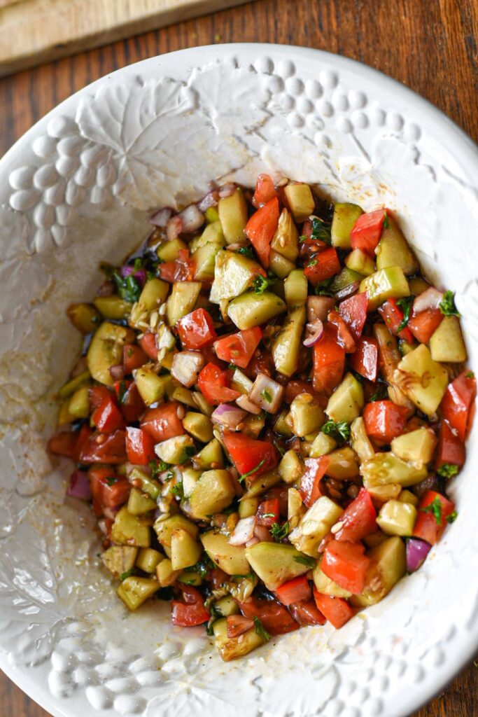 Diced cucumber tomato balsamic salad mixed together in a large white bowl
