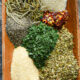 A close up of the spices used for spaghetti seasoning in a wooden bowl prior to being mixed.