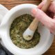 A hand using a mortar and pestle to grind mediterranean diet spices.