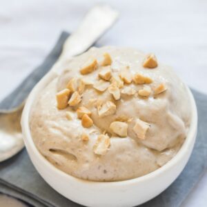 A white bowl filled with banana nicecream on a grey napkin