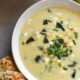 A bowl of yellow poblano corn chowder topped with cilantro and next to a piece of toasted sourdough bread