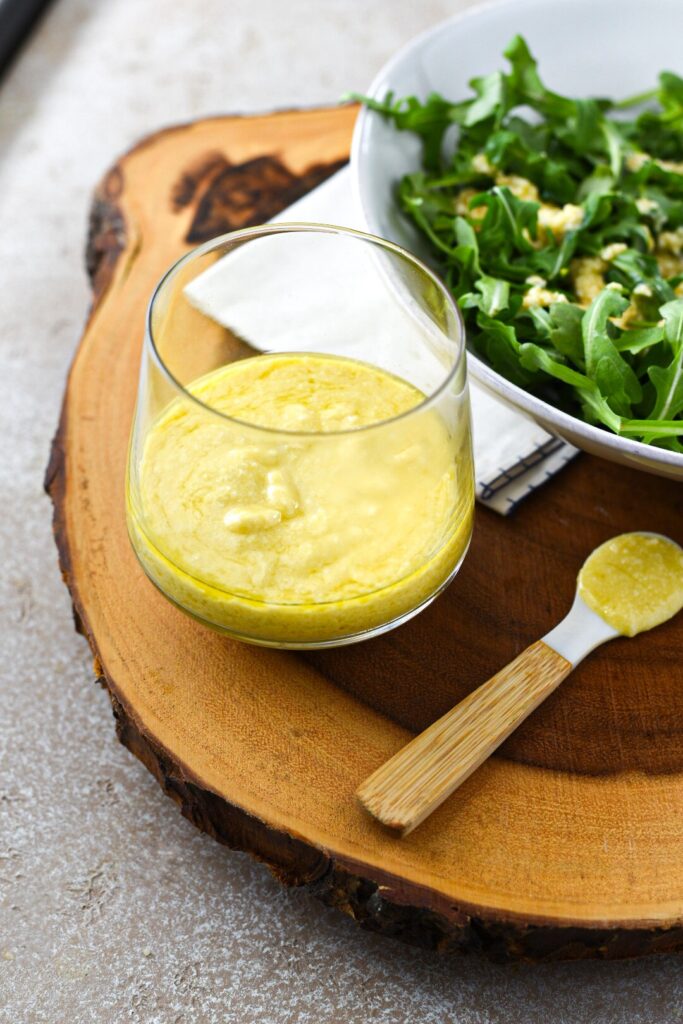 Garlic parmesan vinaigrette on a wooden board next to a salad