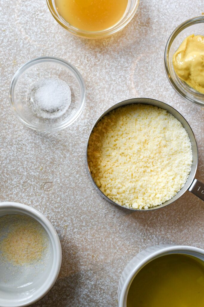 Overhead shot of the ingredients needed for parmesan vinaigrette in separate bowls