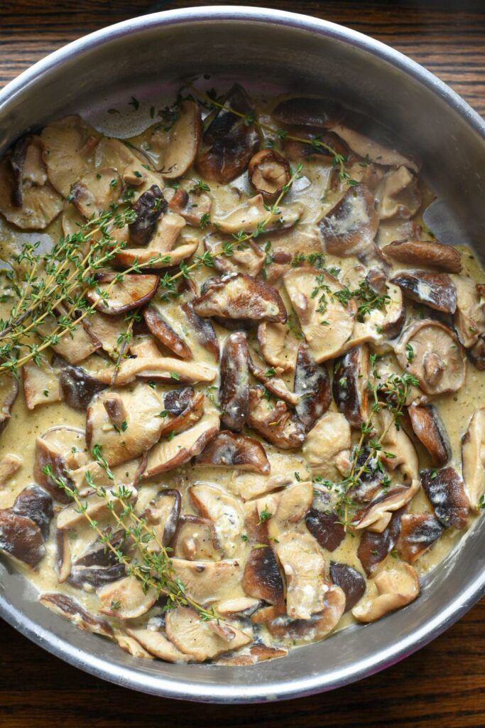 An overhead photo of cheesy shiitake mushrooms covered in fresh thyme