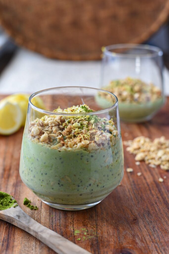 green matcha overnight oats in a glass with matcha and lemon on the surface