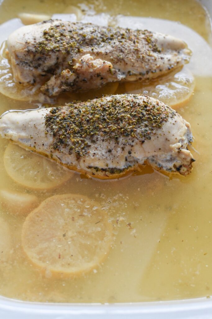 Chicken breasts marinading in lemon broth in a slow cooker