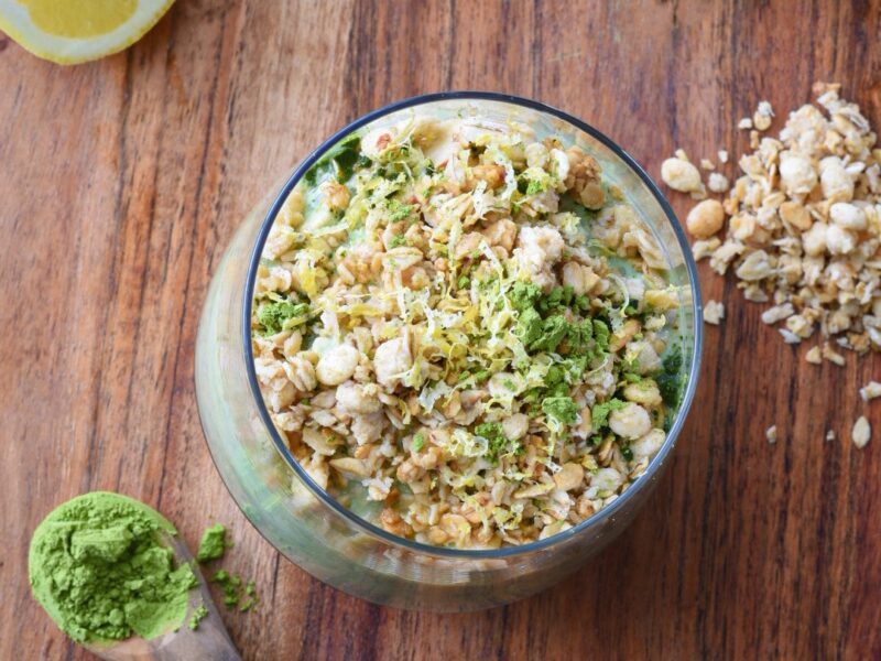 An overhead shot of overnight oats with matcha in a large mason jar with lemons in the corner