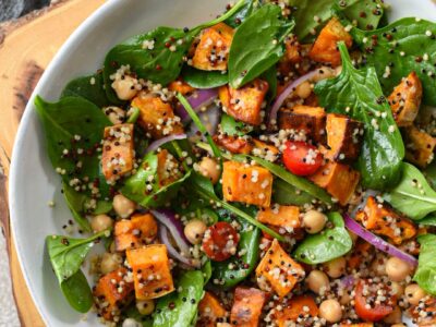 An overhead shot of sweet potato quinoa salad in a bowl with salad, red onion, tomatoes and chickpeas.