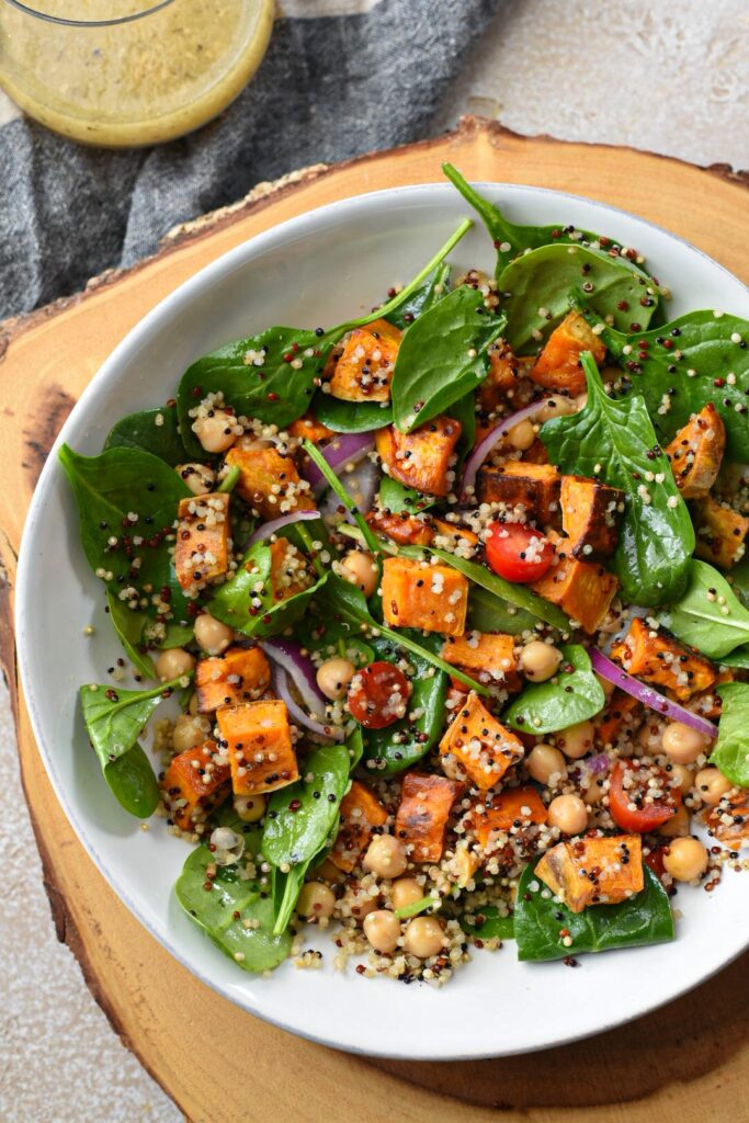 An overhead shot of sweet potato quinoa salad in a bowl with salad, red onion, tomatoes and chickpeas.