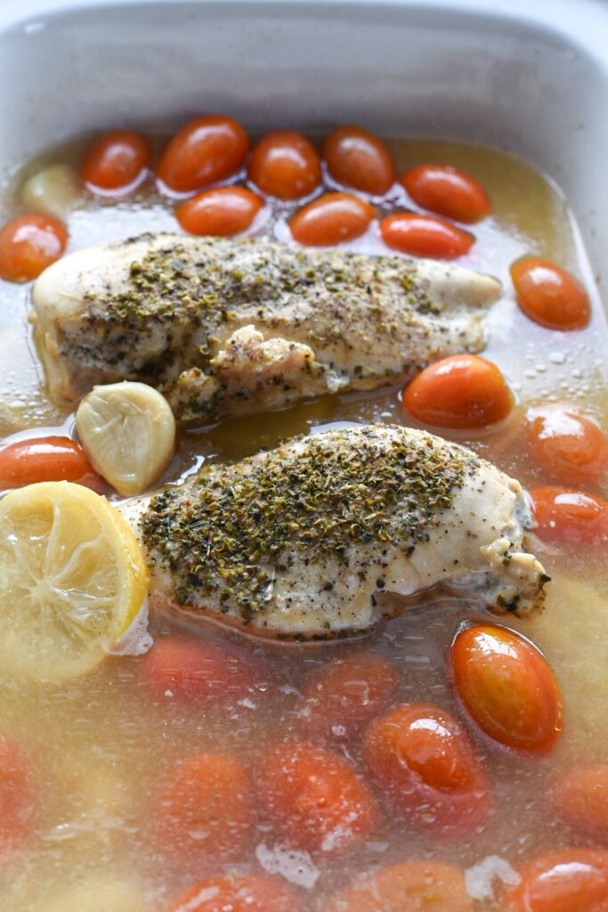 A crockpot filled with slow cooked lemon chicken with cherry tomatoes and broth.