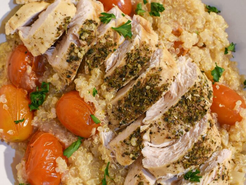 slow cooker lemon chicken recipe Close up of sliced herb chicken breast on quinoa surrounded by cherry tomatoes and parsley
