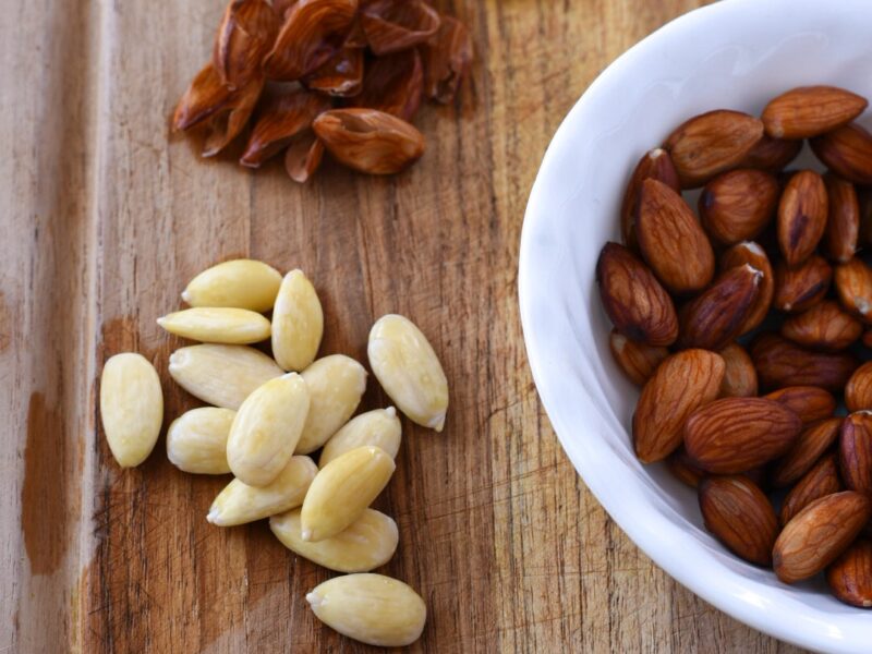 Almonds that have been blanched with their skin off on a wooden cutting board