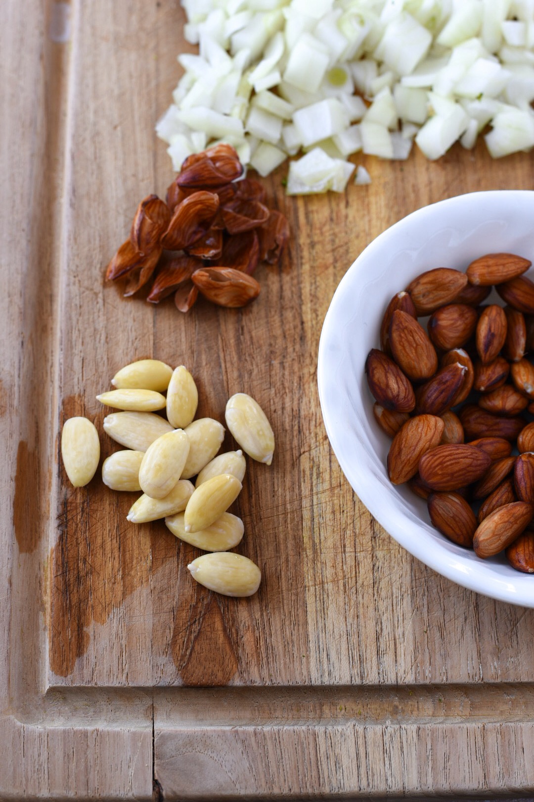 Almonds that have been blanched with their skin off on a wooden cutting board