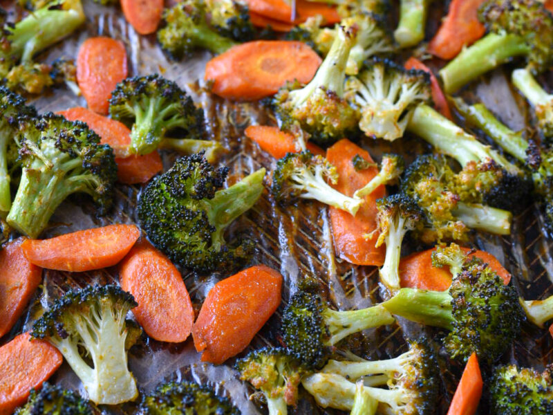 Roasted broccoli and carrots with honey dijon sauce on a baking sheet