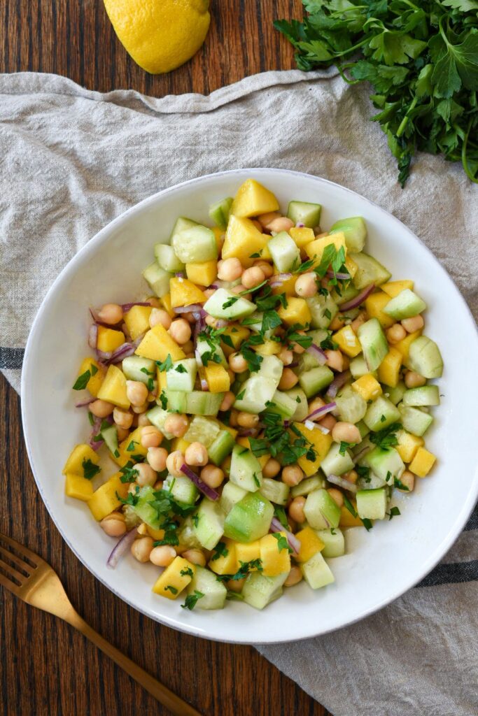 An overhead shot of mango and cucumber salad on a wooden surface