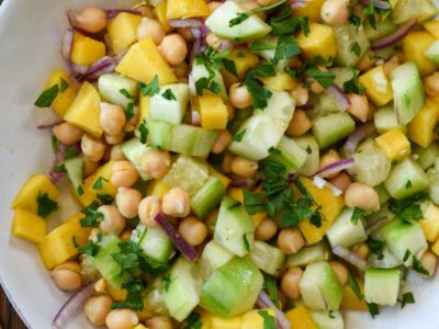 An overhead shot of cucumber mango salad with chickpeas and red onion in a white bowl