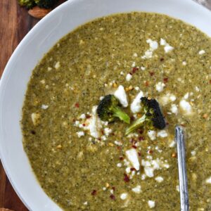 Broccoli feta soup sprinkled with feta and red pepper flakes in a white bowl