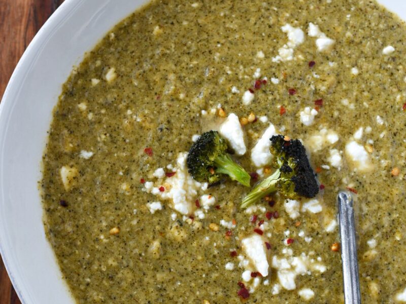 Broccoli feta soup sprinkled with feta and red pepper flakes in a white bowl