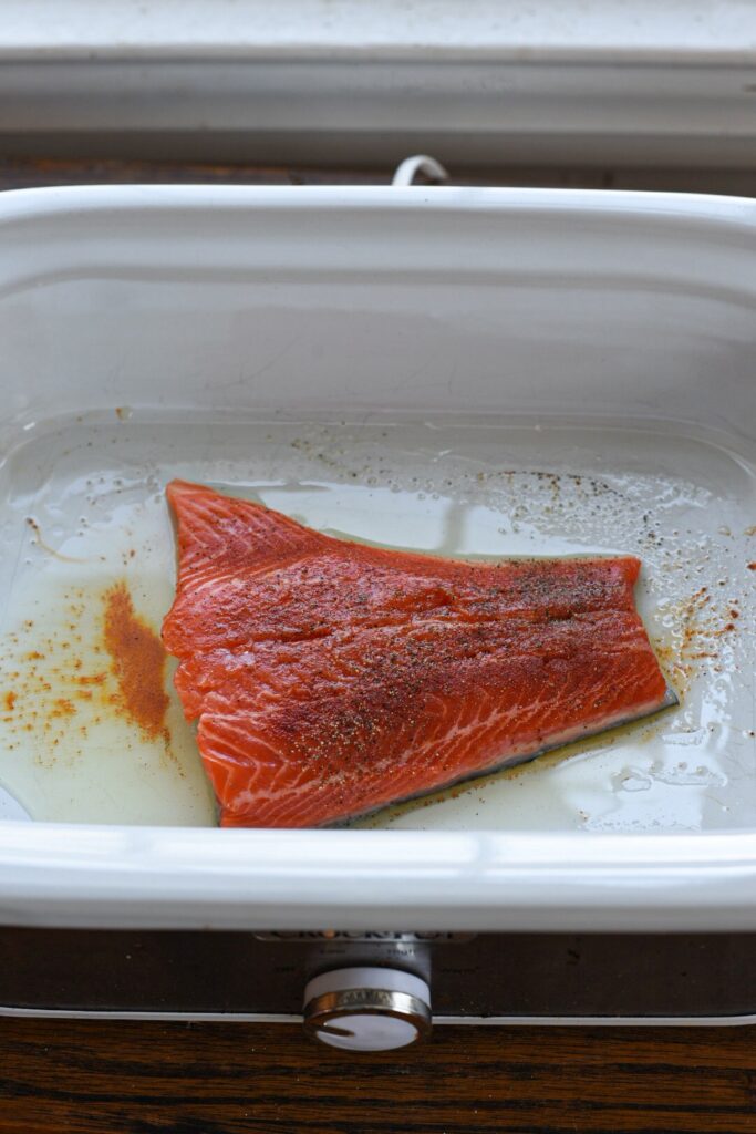 a piece of salmon in crockpot with seasonings on it