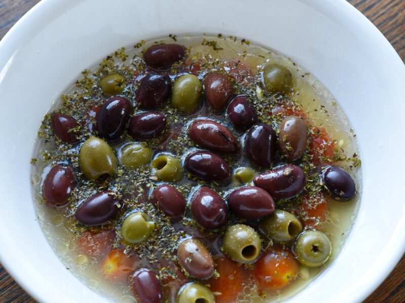 slow cooker salmon and olives Green and kalamata olives in a white bowl with cherry tomatoes, italian seasoning, broth, lemon juice and white wine.