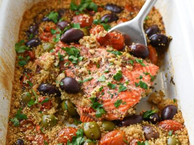 salmon in a slow cooker with olives, tomatoes and quinoa being lifted out by a spatula