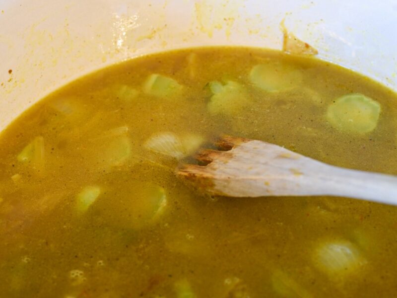 curried broccoli stem soup in a pot with a wooden spoon