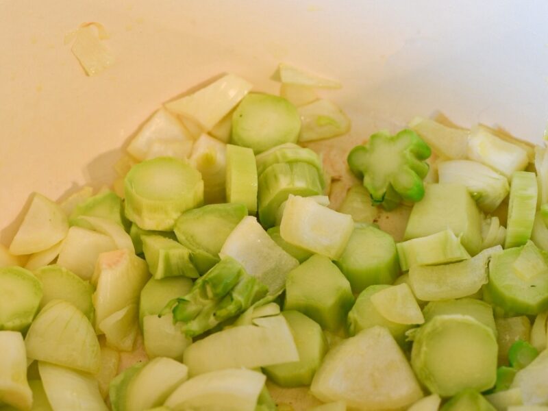 broccoli stems sauteing in a pot with onion for curried broccoli stem soup