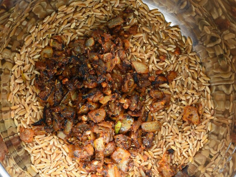 instant pot kamut side The inside of an instant pot with uncooked kamut kernels and onion and spices