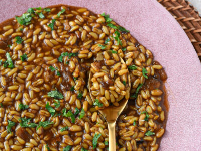 A pink plate filled with a kamut instant pot recipe with a gold spoon and parsley on the kamut