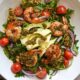 A close up overhead image of a shrimp and pesto buddha bowl with rice, quinoa, red onion, and tomatoes.