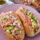 A chopped italian sandwich on a pink plate with italian sandwich dressing in the background
