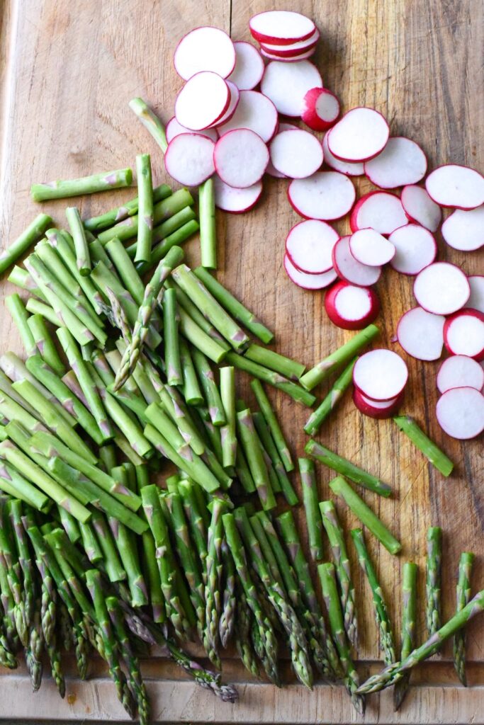Chopped asparagus and radishes on a wooden cutting board